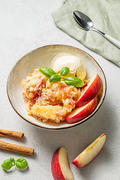 istock Peach crumble or cobbler with vanilla ice cream scoops and cinnamon on a plate on a light background 2235526465