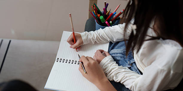 istock Creative Learning. Young girl drawing and writing in a notebook at home. 2235528146