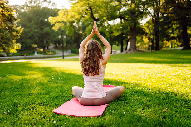 istock A young woman practices on a yoga mat in a sunny park. 2235530862
