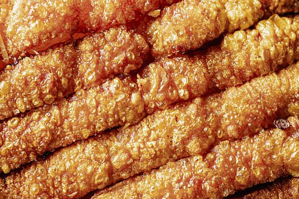 Close-up of crispy golden pork cracklings showcasing their textured surface. Perfect for food lovers, culinary enthusiasts, and snack aficionados, this image captures the delicious appeal of this savory treat.