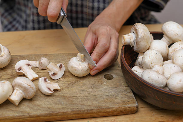 istock Woman cutting champignons. Cooking with champignons. Selective focus. 2235532695