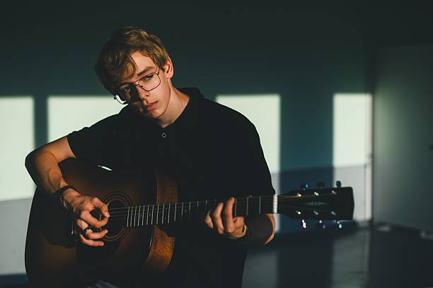 istock High school student playing acoustic guitar in classroom. 2235533433