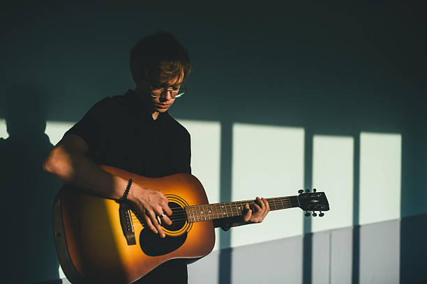 istock High school student playing acoustic guitar in classroom. 2235533440