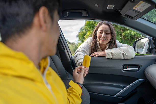 istock Man Offering Ice Cream To Woman Through Car Window 2235534332