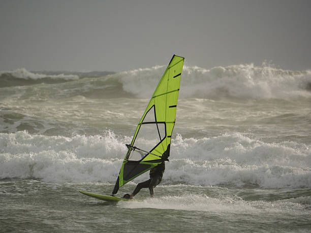 istock Water Sport Activity - Windsurfer Riding a Wave in Rough Sea on a Windy Day 2235534406