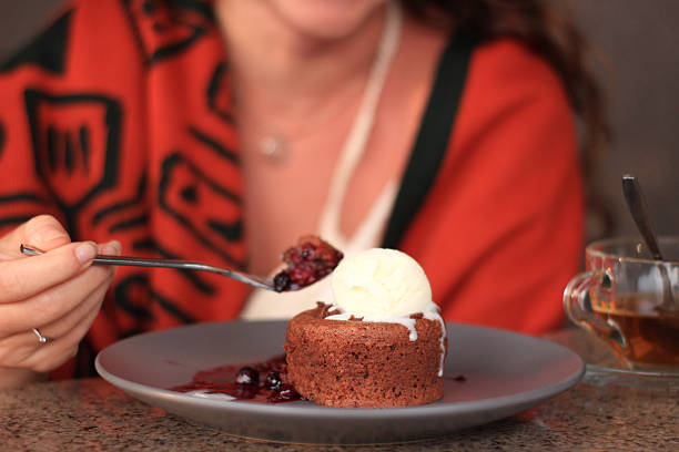 Image of vanilla ice cream with berry sauce on a gray plate, with tea nearby.