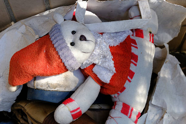 End of the childhood: snowman, a toy abandoned in the rubbish