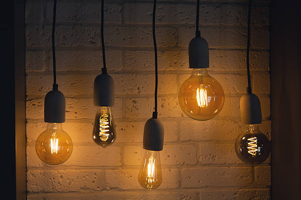 istock Vintage-style light bulbs hanging against a white background 2235537040
