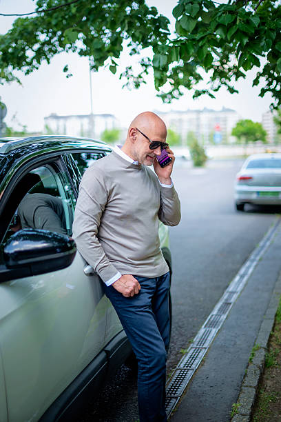 istock Middle aged man using smart phone and standing next to his car in the street 2235537689