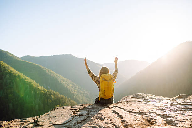 istock A female hiker with a bright yellow backpack sits on a cliff and looks at the mountain range. 2235538288