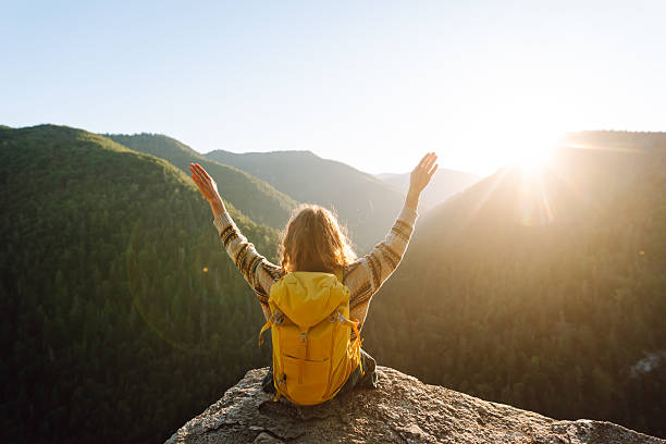istock A female hiker with a bright yellow backpack sits on a cliff and looks at the mountain range. 2235538312