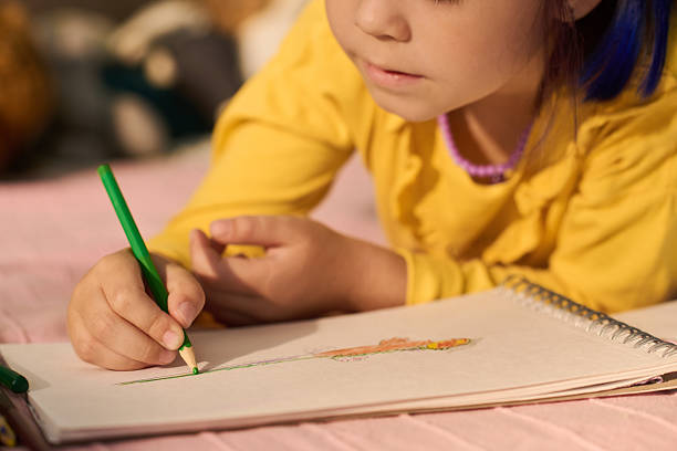 istock Girl Child Drawing with Colored Pencil While Lying on Bed 2235540147