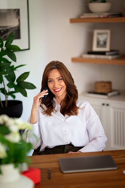 istock Attractive middle aged female using her laptop and smart phone at home 2235540297