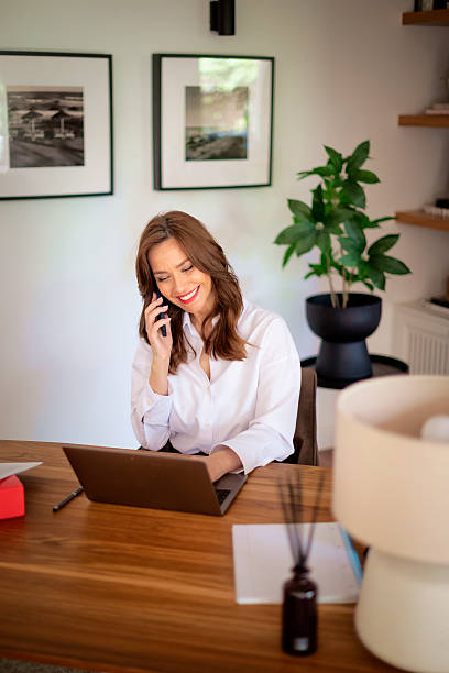 istock Attractive middle aged female using her laptop and smart phone at home 2235540315