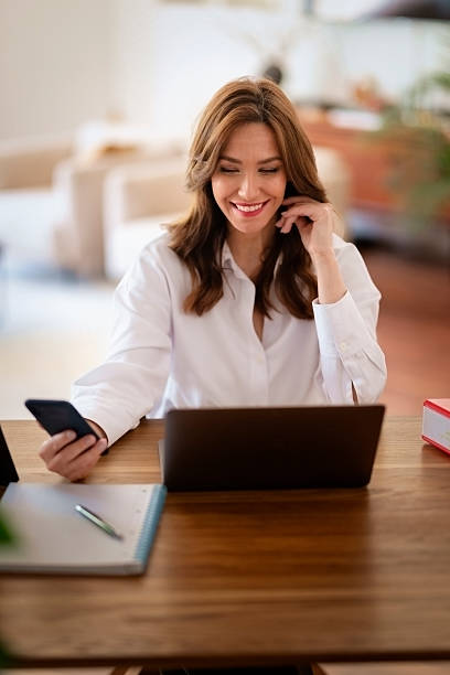 istock Attractive middle aged female using her laptop and smart phone at home 2235540339