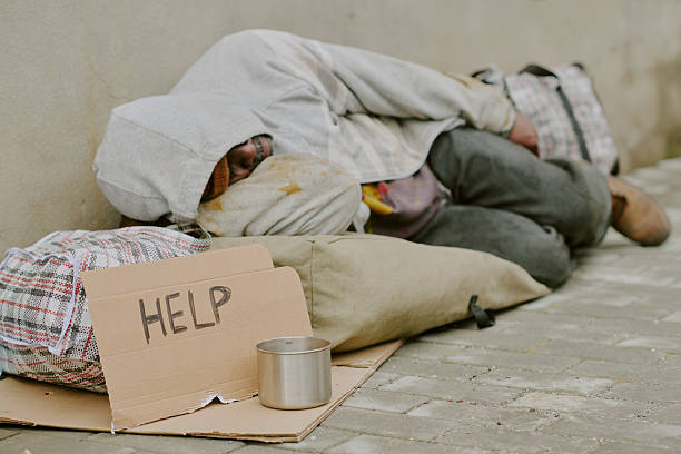 istock Homeless Black Man Sleeping Outdoors Requesting Assistance with Sign 2235540945