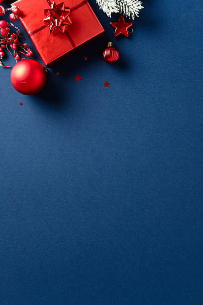 istock Xmas vertical background with red gift box, bauble, star, pine branch and berries on dark blue background. Merry Christmas vertical banner design. 2235543543