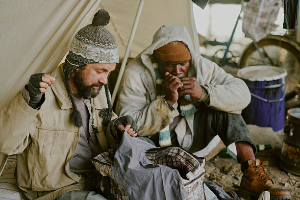 istock Homeless Caucasian Man and Black Man Sitting Outdoors Sharing Meal 2235543664