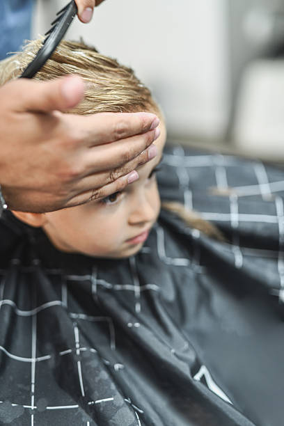 istock Attentive Boy Sitting Still For His Haircut 2235544400