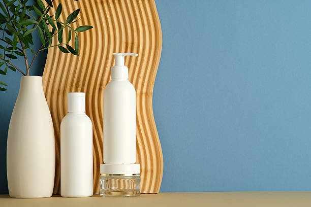 istock Minimal personal care scene with white bottles, ceramic vase, and wooden panel on blue background. Clean composition ideal for skincare, wellness, and product branding. 2235545098