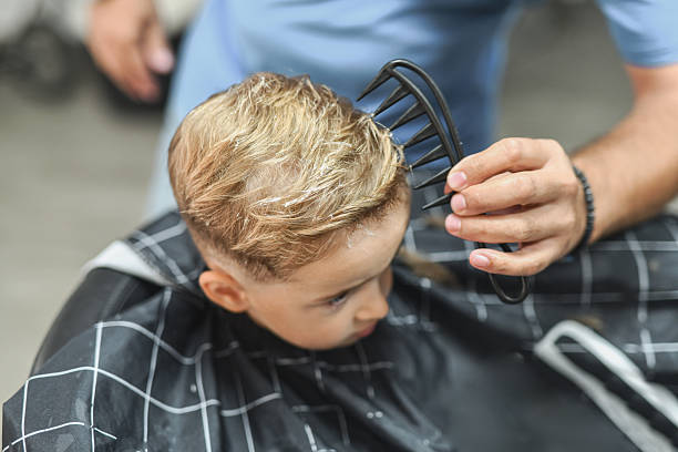 Barber Perfecting Young Boy’s Hairstyle With Comb