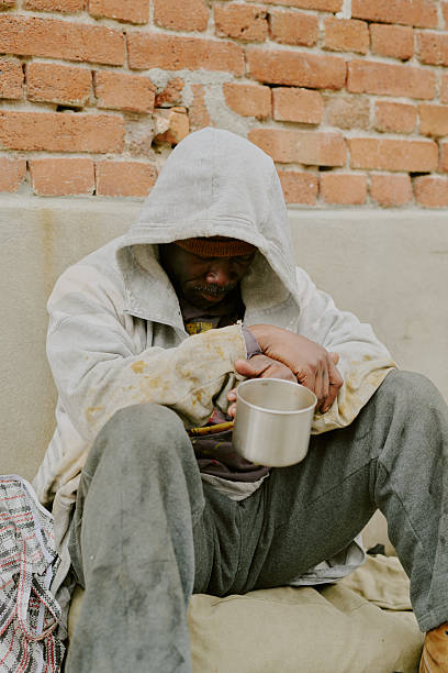 istock Homeless Black Man Sitting Outdoors Holding Metal Cup Begging for Help 2235545910