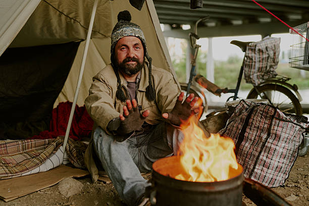 istock Homeless Caucasian Man Warming Hands by Campfire under Urban Bridge 2235546136