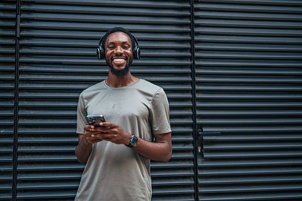 istock Young man listening to music and using phone in urban setting 2235549002