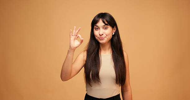 istock Happy woman smiling brightly and confidently forms Okay gesture 2235550074