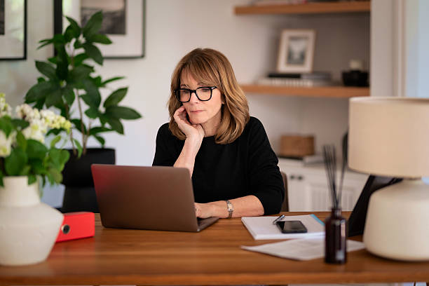 istock Blond haired woman sitting at desk and using laptop 2235550990