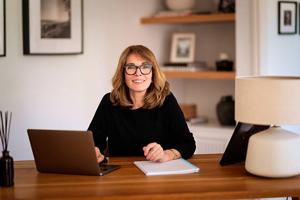 istock Blond haired woman sitting at desk and using laptop 2235550997