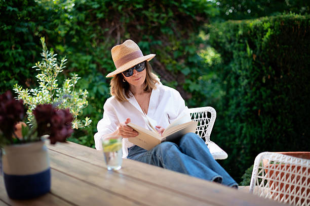 istock Middle aged woman sitting at balcony at home and reading a book 2235552293
