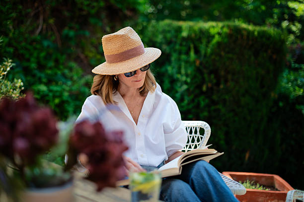 istock Middle aged woman sitting at balcony at home and reading a book 2235552305