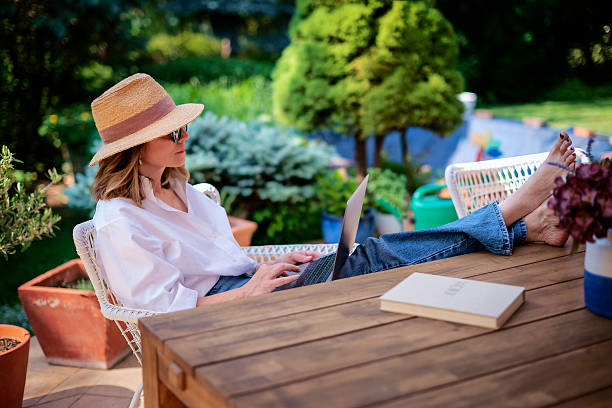 istock Mature woman sitting outdoor in back yard and using a computer laptop 2235552316