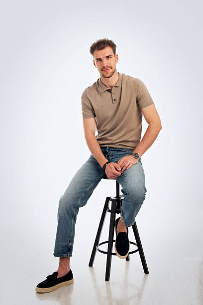 istock Handsome young man sitting against isolated white background 2235554835