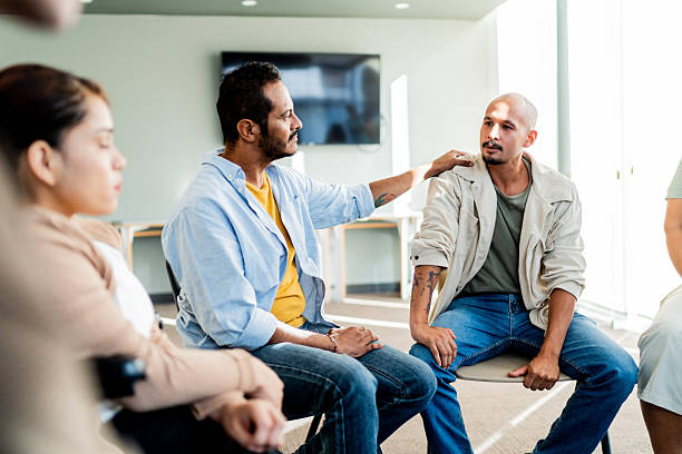 istock Mid adult man being comforted during group therapy 2235556091