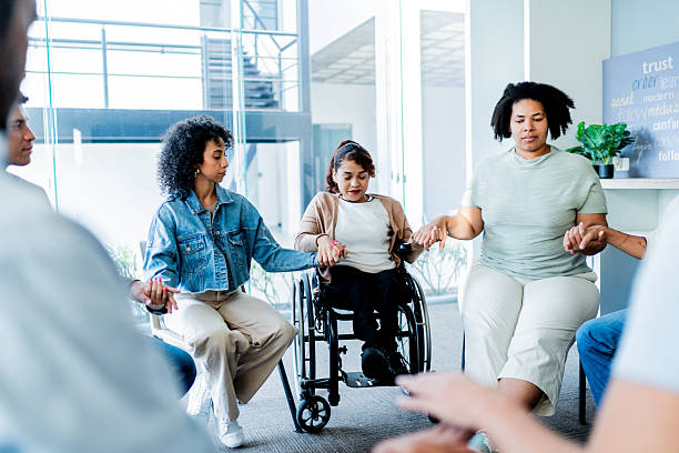 istock People holding hands during group therapy session - Including a wheelchair woman 2235556113