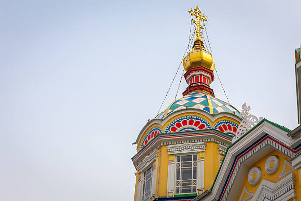 The Ascension Cathedral (Zenkov Cathedral), Russian Orthodox church colorful dome and decorative tower with golden cross against blue sky, Almaty, Kazakhstan, copy space.