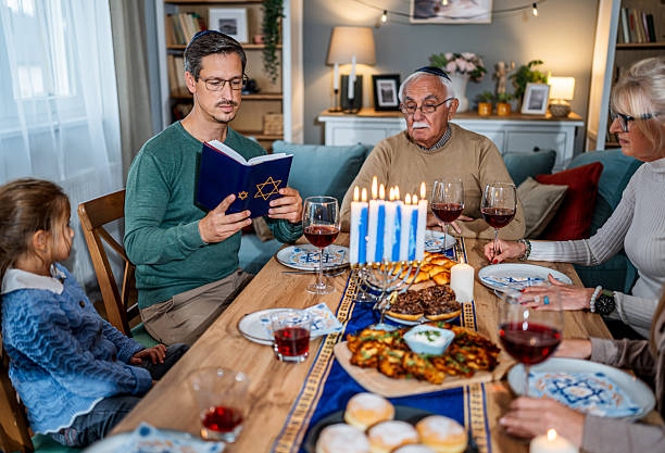istock Family celebrating Hanukkah reading from the torah at dinner table 2235560947
