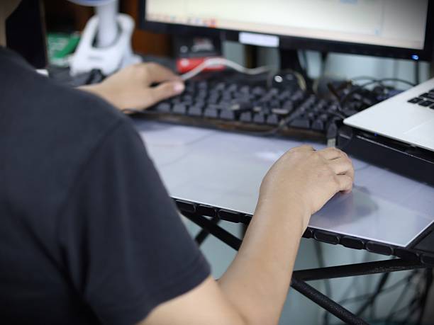 istock This image shows a person working at a computer desk, with their hands resting on the keyboard and mouse, indicating that they are actively using the computer. 2235561384