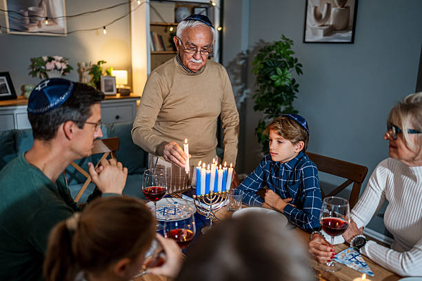 istock Family celebrating Hanukkah lighting menorah candles during dinner 2235561646
