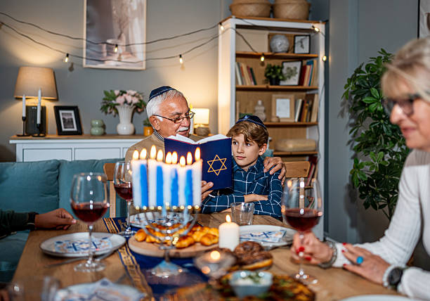 istock Family celebrating Hanukkah reading from the torah at dinner table 2235562871