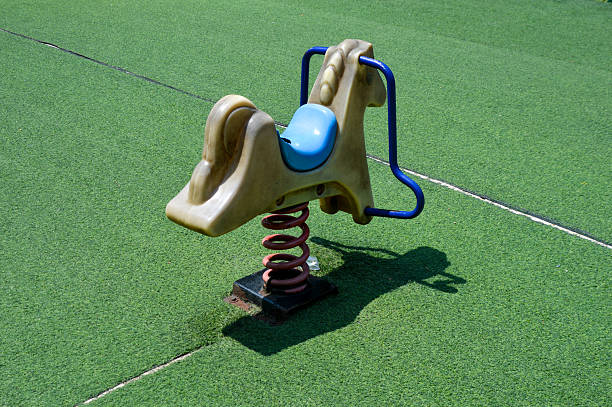 Seesaw in red duck shape, children outdoors playground toy. Soft cork flooring. Galicia, Spain.