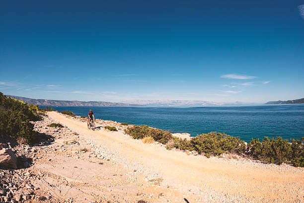 istock Cyclist Riding Along Rocky Coastal Trail 2235566125