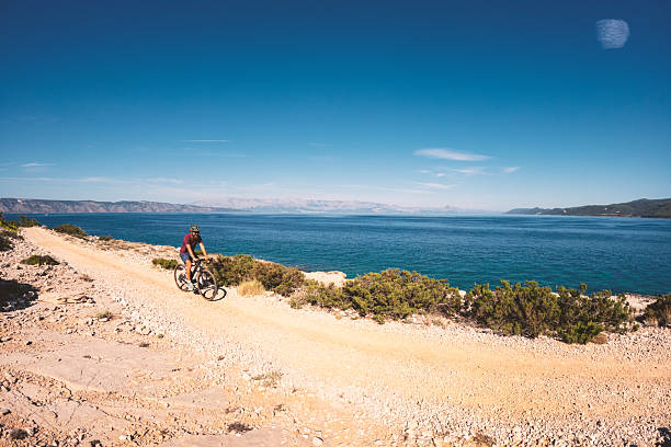 istock Cyclist Riding Along Rocky Coastal Trail 2235566176