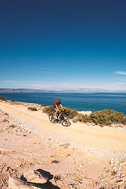 istock Cyclist Riding Along Rocky Coastal Trail 2235566192