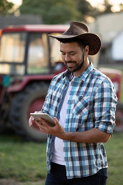 istock Farmer with hat using tablet on farm during the day 2235568811