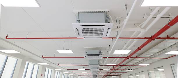 istock Modern office ceiling with exposed air conditioning ducts and red pipes. 2235569558