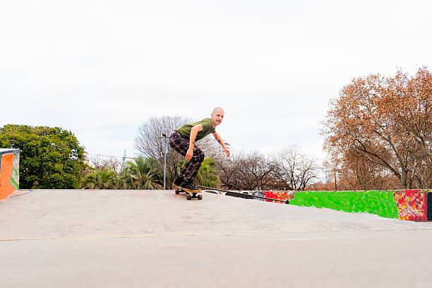 Mid adult man doing skateboard tricks at public park