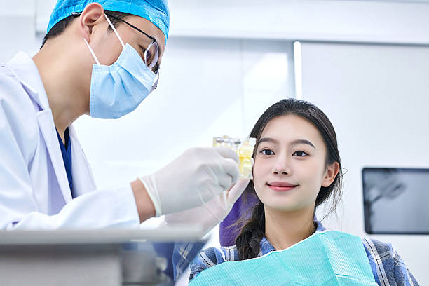 istock Dentist Holding Dental Mold Explaining to Female Patient 2235585270